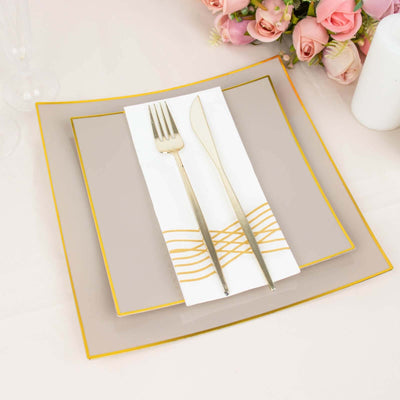 Elegant dining set with gold-accented plates and silverware on a soft table setting.