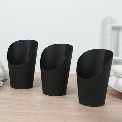 Set of three black decorative cups on a wooden table.