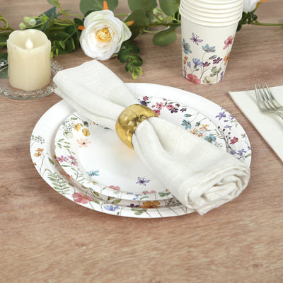 Floral dinnerware set with a napkin and gold napkin ring on a wooden table.