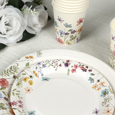 Floral-themed disposable plates and cups arranged with decorative flowers.