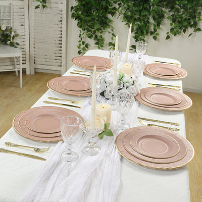 Elegant dining table set with pink plates, candles, and glassware.