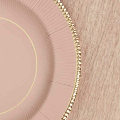 Pink paper plate with gold rim detail on a textured surface.