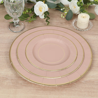 Pink decorative plates with gold accents on a wooden table setting.