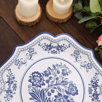 Decorative blue and white floral plate on wooden table with candles and greenery.