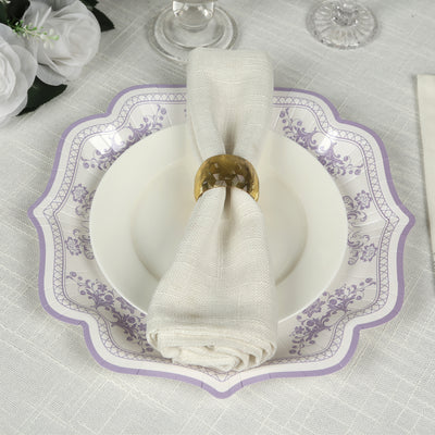 Elegant white plate with purple floral design and napkin holder on a textured table setting.