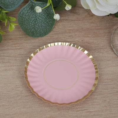 Pink decorative plate with gold rim on a wooden surface.