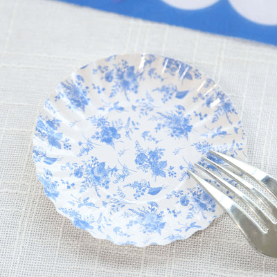 Blue floral paper plate with fork on a textured surface.