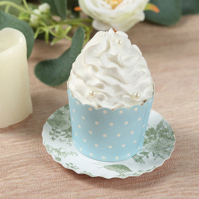 Blue polka dot cupcake with whipped cream and decorative pearls on a floral plate.