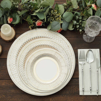Elegant dinnerware set with decorative plates and cutlery on a rustic wooden table.