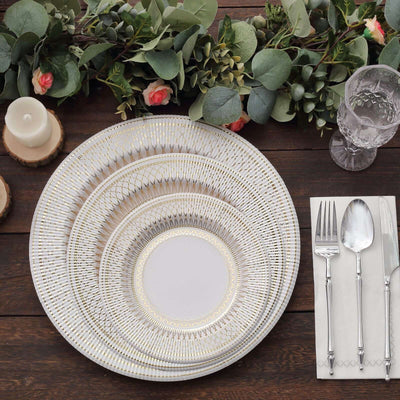 Elegant white and gold dinnerware set on a rustic wooden table.