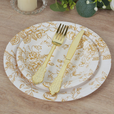 Gold floral disposable plates with matching cutlery on a wooden table.
