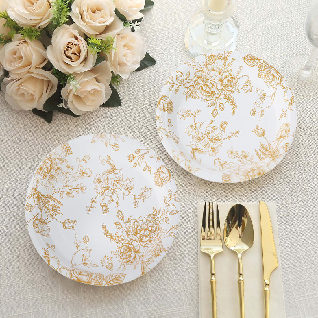 Elegant gold floral dinner plates set on a textured table with roses.