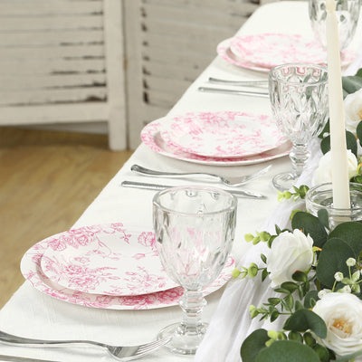 Pink floral dinner plates and crystal glassware set on a table for dining.