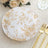 Elegant gold floral design paper plate on a textured table setting.