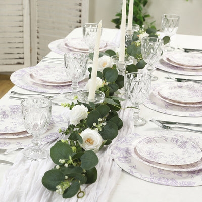 Elegant table setting with floral plates, glassware, and greenery accents.