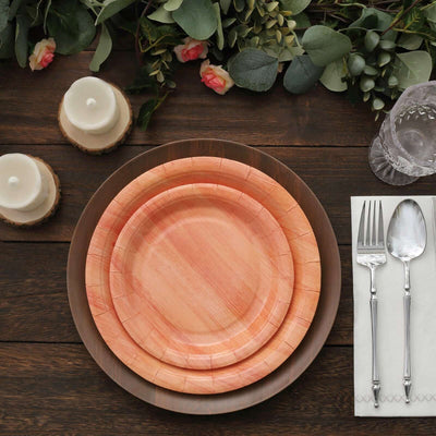 Wooden plates set on a rustic table with candles and greenery decor.
