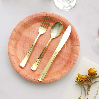 Gold cutlery set on a pink wooden plate for elegant dining.