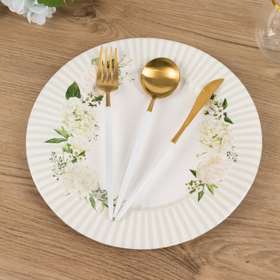 Gold cutlery set on floral plate against wooden table backdrop.