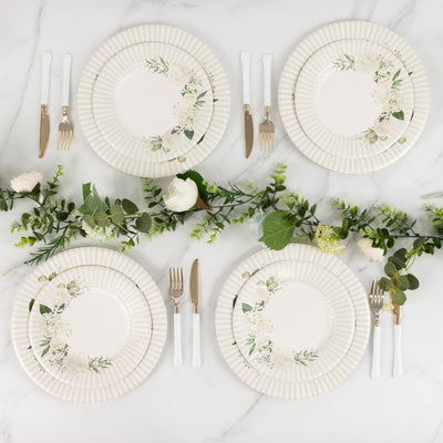 Elegant floral dinner plates arranged with cutlery and greenery.