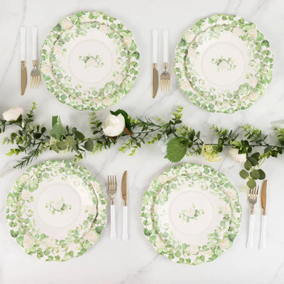 Floral dinner plates arranged with greenery on a marble table.