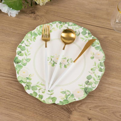 Floral paper plate with gold utensils on a wooden table.