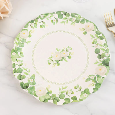 Floral decorative plate with green leaves and white flowers on a marble surface.