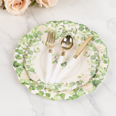 Floral paper plates with white utensils on a marble surface.