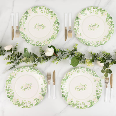 Floral dinner plates arranged with cutlery and greenery on a marble surface.