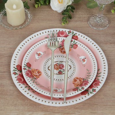 Elegant pink floral dinnerware set with silver cutlery on a wooden table.