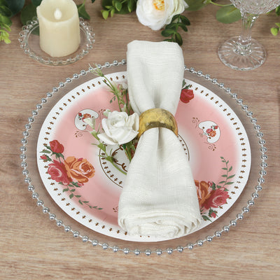 Elegant pink floral dinner plate with napkin and ring on a wooden table setting.