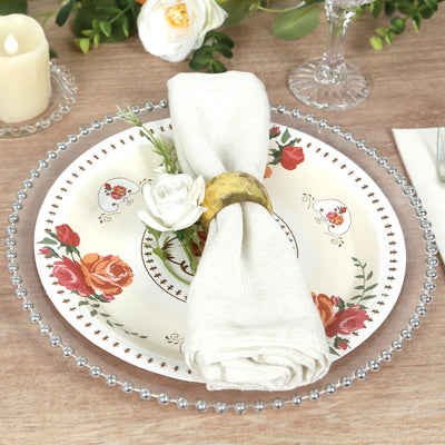 Elegant floral dinner plate with napkin and gold ring on rustic table setting.