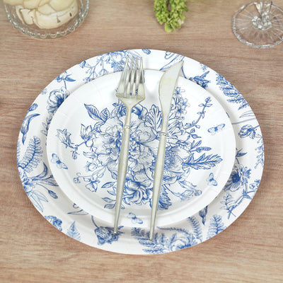 Elegant blue floral paper plates with silver utensils on a wooden table.