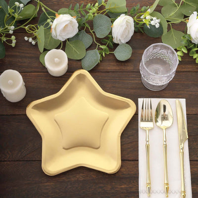 Gold star-shaped plate with utensils and candles on a wooden table.