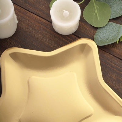 Gold star-shaped plate on wooden surface with candles and greenery.