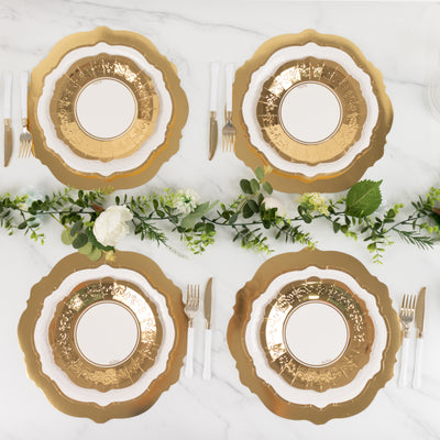 Elegant gold-accented dinnerware set on a marble table with greenery.