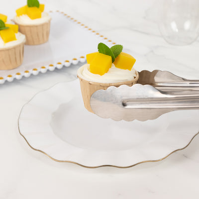 Cupcake with mango topping and mint leaf, served on a decorative plate.