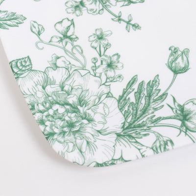 Green floral botanical print on white ceramic plate close-up