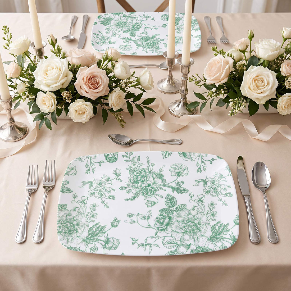 Elegant floral wedding table setting with roses, candles, and green patterned plates