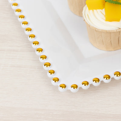 White serving platter with gold accent and decorated cupcakes on a wooden surface.