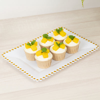 Delicious mango cupcakes with cream and mint leaves on a decorative platter.