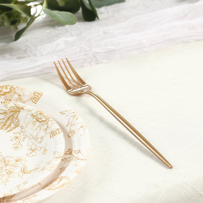 Elegant gold fork beside a floral-patterned plate on a table setting.