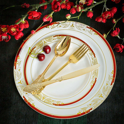 Elegant gold cutlery on a decorative plate with cherries and flowers.