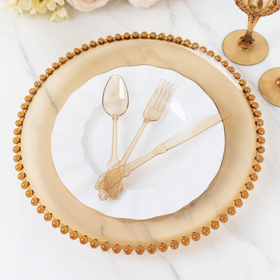 Elegant gold-rimmed plate set with cutlery and glassware on a marble surface.