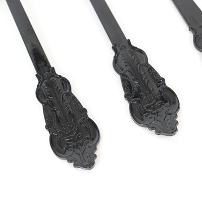 Black ornate metal serving utensils on a white background.