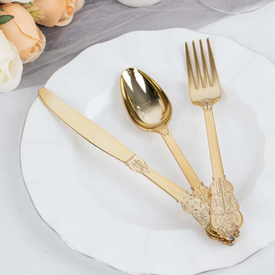 Elegant gold cutlery set on a white plate with floral arrangement.