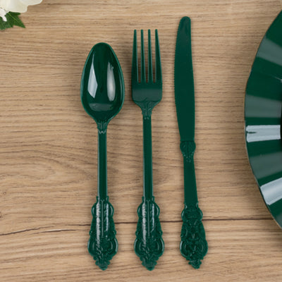 Green plastic cutlery set with spoon, fork, and knife on wooden table.