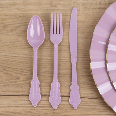 Purple plastic cutlery set including spoon, fork, and knife on wooden surface.