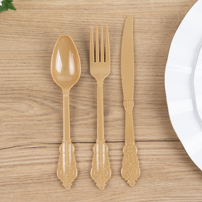 Elegant gold plastic cutlery set on wooden table.