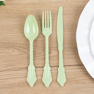 Green plastic cutlery set including spoon, fork, and knife on wooden table.