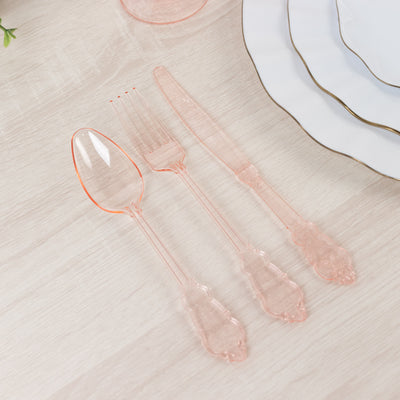 Elegant pink plastic cutlery set on a wooden table.